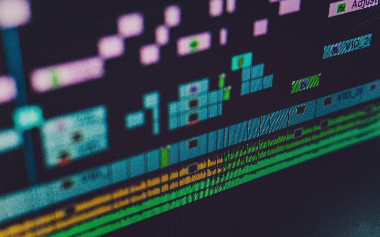 Close-up of a video editing timeline with clips, effects labels and audio waveforms on screen