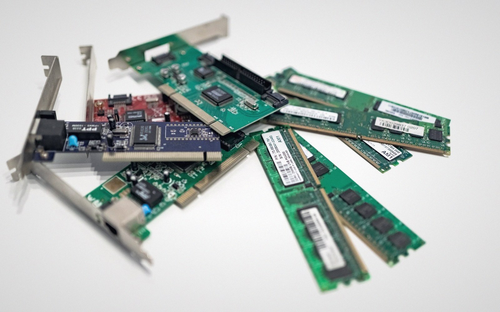A pile of computer memory sticks and expansion cards on a white surface